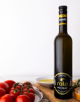 Bottle of Argolid olive oil with tomatoes and bread on a wooden board