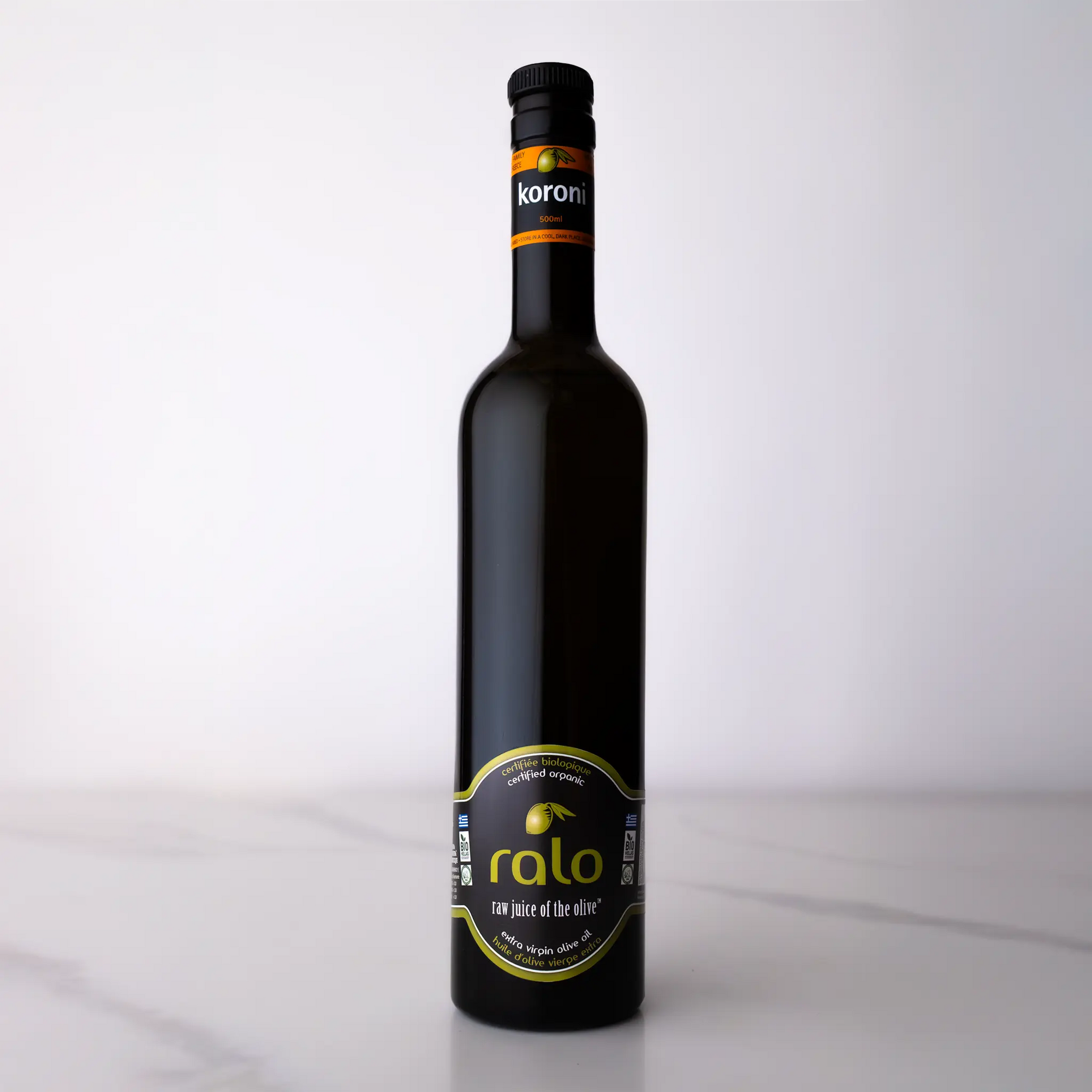 Black koroni olive oil bottle with a label on a white background