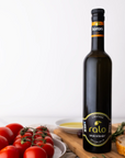 Bottle of Koroni olive oil on a wooden cutting board with tomatoes and bread.